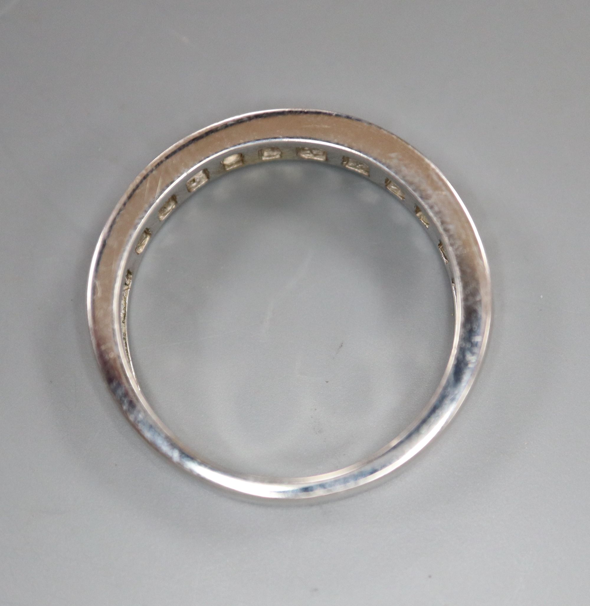 A modern 750 white metal and channel set twenty stone diamond half eternity ring, size O, gross 3.9 grams.
